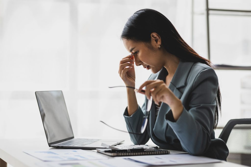 tired asian businesswoman in front of laptop