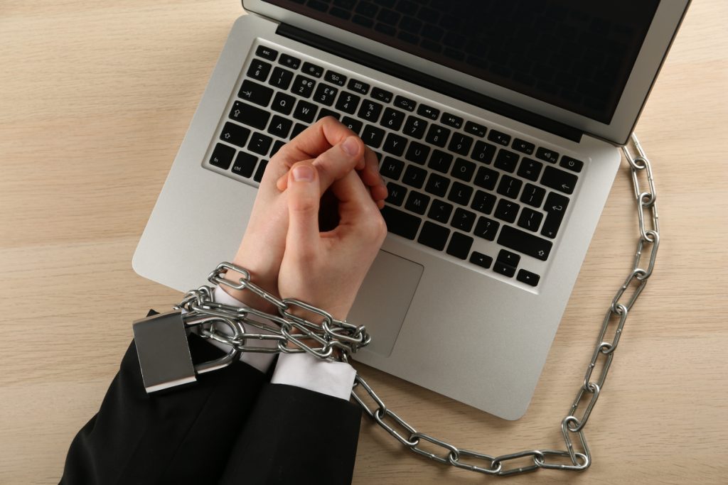 Man's hands chained near laptop